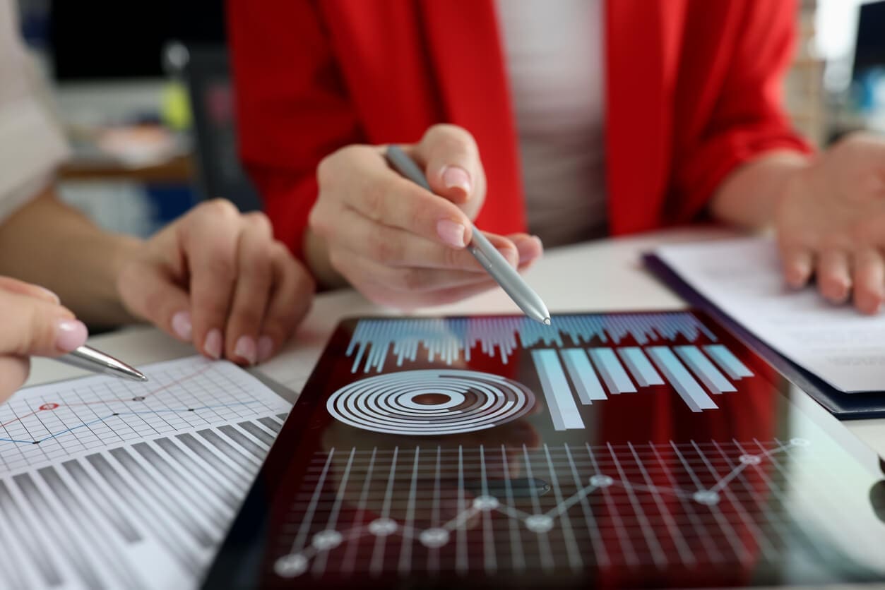 business-women-studying-charts-and-diagrams-on-digital-tablet-closeup