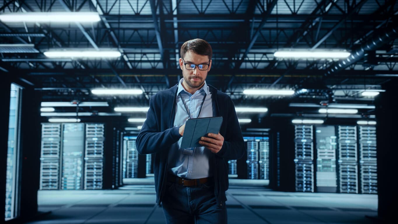 male-it-specialist-walks-between-row-of-operational-server-racks-in-data-center-2